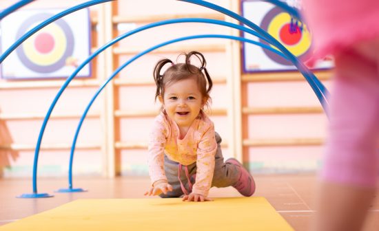 Baby crawling on floor in gym class. Lifestyle concept of children activity. Baby girl crawling on mat in gym class. Lifestyle concept of children activity.